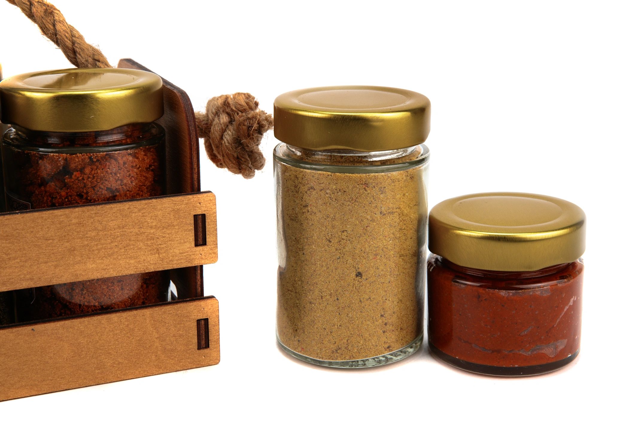 A set of spices in glass jars, packed in a wooden box with a rope handle