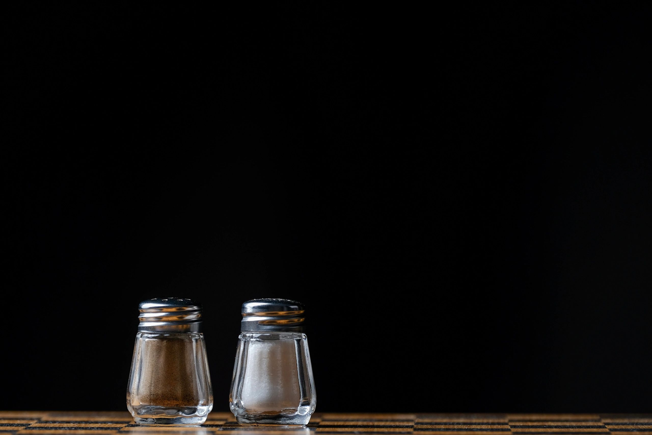 Glass spice shakers on a wooden table with dark background
